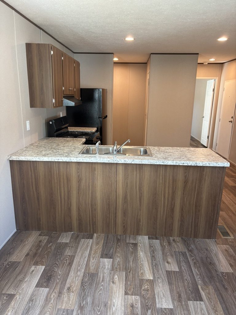 Kitchen peninsula with double sink and hallway to the bedrooms